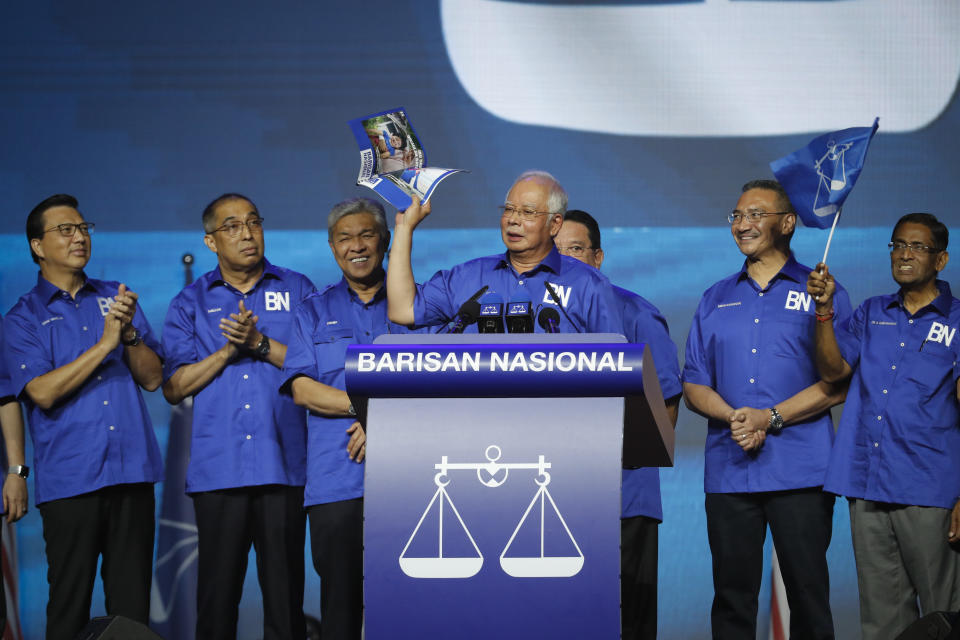 FILE - Malaysia's Prime Minister and President of the ruling party coalition "National Front,"Najib Razak, center, holds a manifesto booklet during launching event for upcoming general elections in Kuala Lumpur, Malaysia, April 7, 2018. Najib Razak on Tuesday, Aug. 23, 2022 was Malaysia’s first former prime minister to go to prison -- a mighty fall for a veteran British-educated politician whose father and uncle were the country’s second and third prime ministers, respectively. The 1MDB financial scandal that brought him down was not just a personal blow but shook the stranglehold his United Malays National Organization party had over Malaysian politics.(AP Photo/Vincent Thian, File)