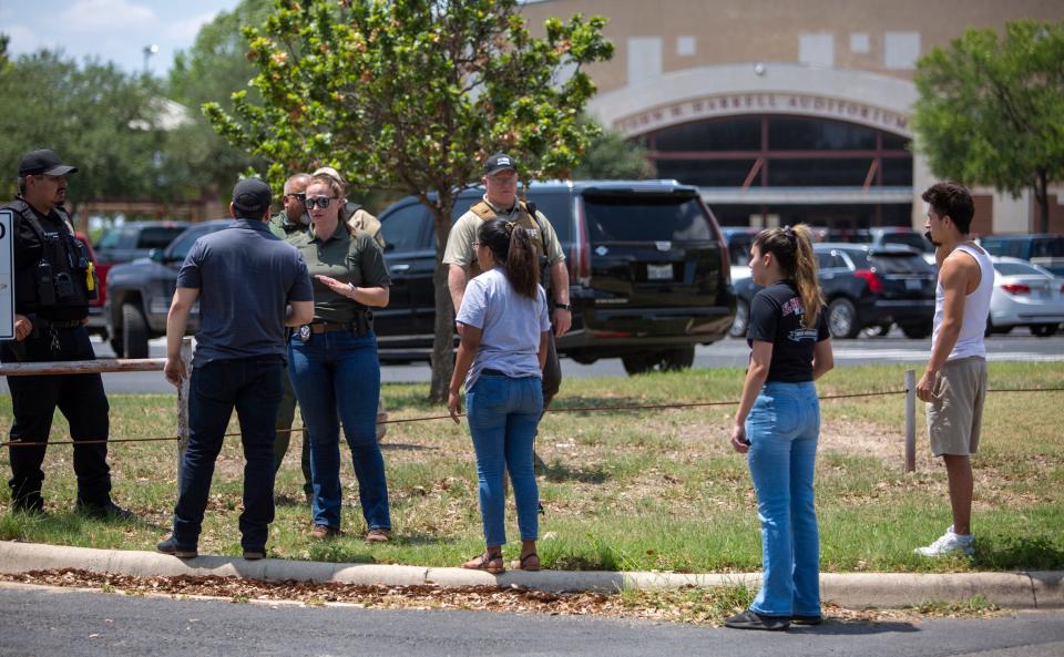 A law enforcement officer speaks with people outside Uvalde High School after shooting a was reported earlier in the day at Robb Elementary School, Tuesday, May 24, 2022, in Uvalde, Texas. 