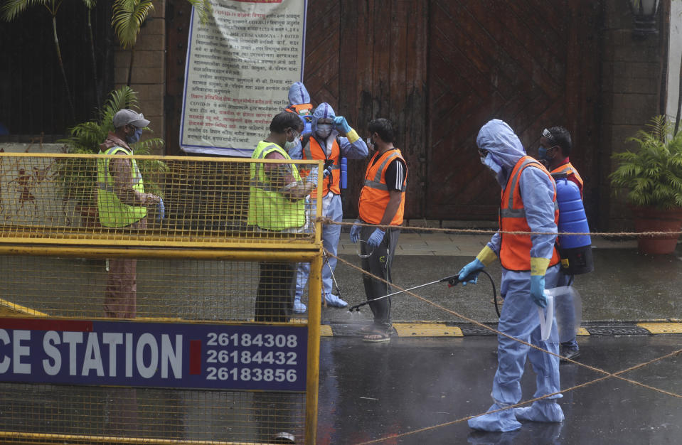 Civic workers sanitize the entrance of Bollywood superstar Amitabh Bachchan's residence after Bachchan and his son tested positive for the coronavirus and were hospitalized in Mumbai, India, Sunday, July 12, 2020. (AP Photo/Rafiq Maqbool)