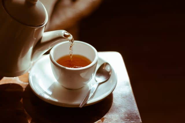 Tea cup on saucer, with tea being poured,