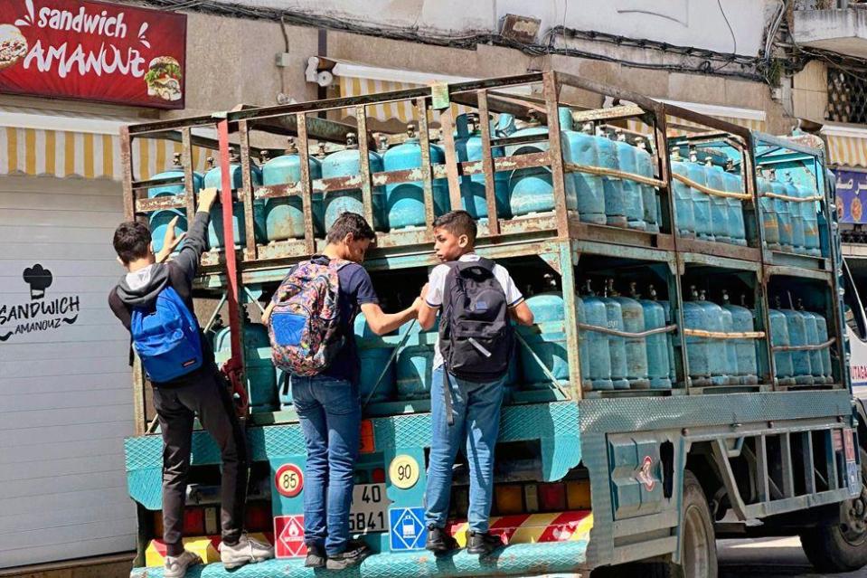 Schoolchildren cling to the back of a truck delivering gas cylinders in Tangier, Morocco - Saturday 11 May 2024