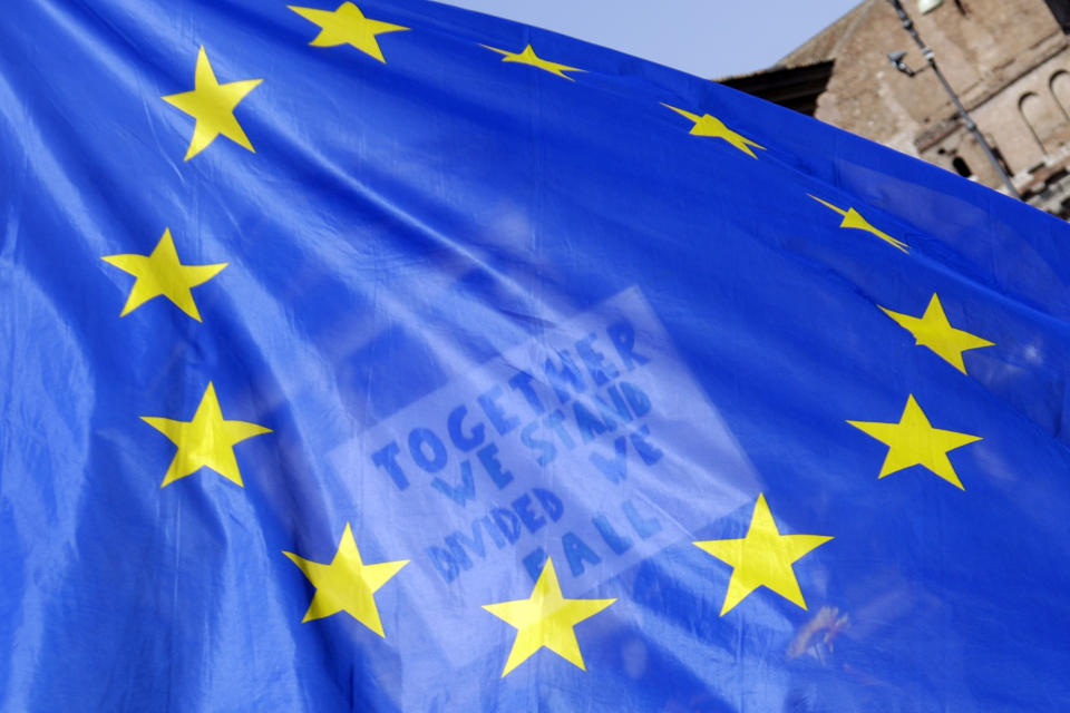 FILE - A placard in support of the European Union is seen through a European flag as demonstrators prepare to take part in a demonstration in support of the European Union in Rome, Saturday, March 25, 2017. On Friday, Sept. 30, 2022, The Associated Press reported on stories circulating online incorrectly claiming a 2013 video showing Italians taking down the European Union flag was filmed after a right-wing group won its national election on Monday. (AP Photo/Gregorio Borgia)