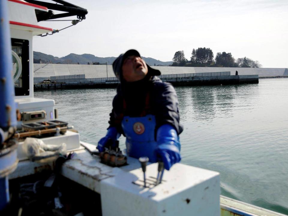 Atsushi Fujita sails his boat as he leaves a dock where sea walls are installed, at Hirota Bay in Rikuzentakata (Reuters)