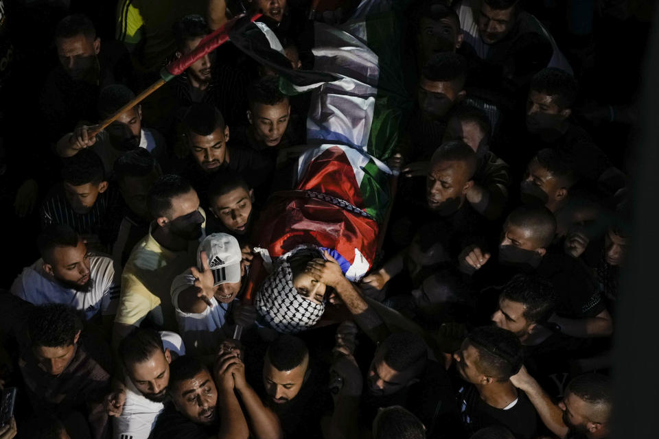 Mourners carry the body of Palestinian Alaa Zaghal during his funeral in Askar refugee camp near the West Bank city of Nablus, Wednesday, Oct. 5, 2022. Israeli troops have exchanged fire with Palestinians during an arrest raid in the occupied West Bank, killing Zaghal and forcing the surrender of another. The Israeli military identified the wanted man an activist in the Islamic militant group Hamas, and said he was suspected in a shooting attack on an Israeli bus and a taxi near Nablus earlier this week. Palestinian medics say at least seven people were wounded. (AP Photo/Majdi Mohammed)