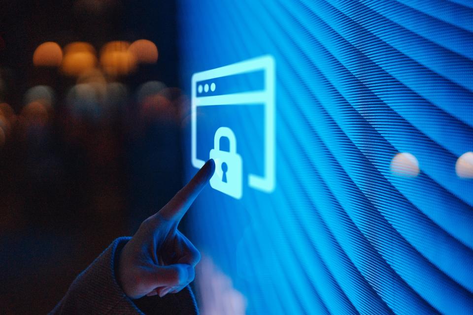 Close-up of a hand touching an illuminated digital screen displaying a padlock