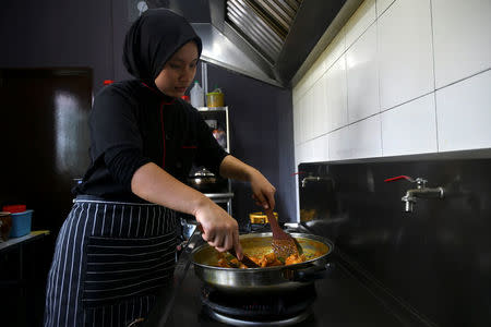 A chef cooks a pot of chicken rendang at a restaurant in Cyberjaya, Selangor, Malaysia April 4, 2018. REUTERS/Stringer