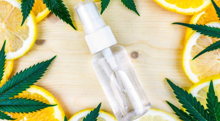 Cannabis Terpene bottle with cannabis leaves and lemon and orange slices on a wooden backdrop