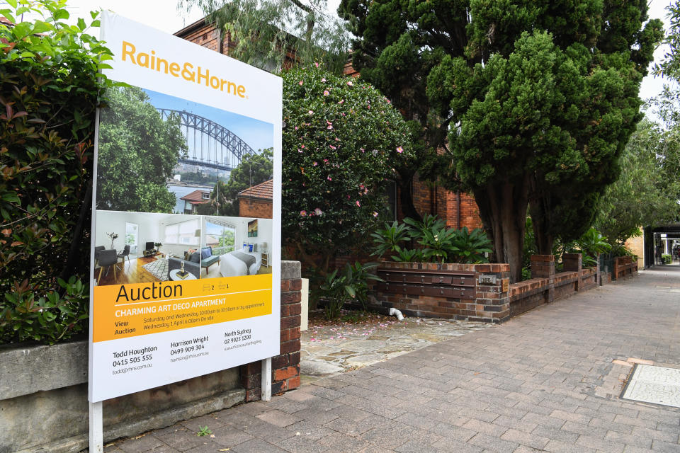 An auction sign outside a house on a suburban Sydney street.