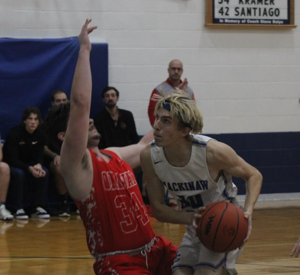 Mackinaw City senior forward Noah Valot (20) takes it to the basket while Onaway junior Justin Kramer-St. Germain (34) defends during the first half.