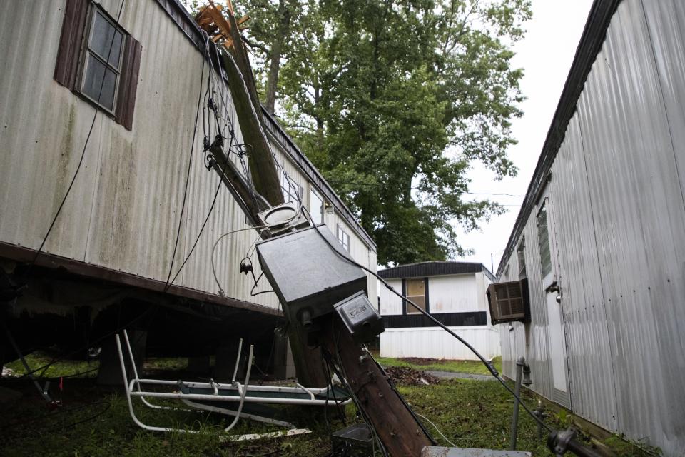 A downed tree lies against a home at Shady Grove Mobile Home Park in Charlotte, N.C., Monday, Aug. 7, 2023. Thousands of U.S. flights have been canceled or delayed as forecasts warn of destructively strong storms, including tornadoes, hail and lightning. (Sean Mcinnis/The Charlotte Observer via AP)