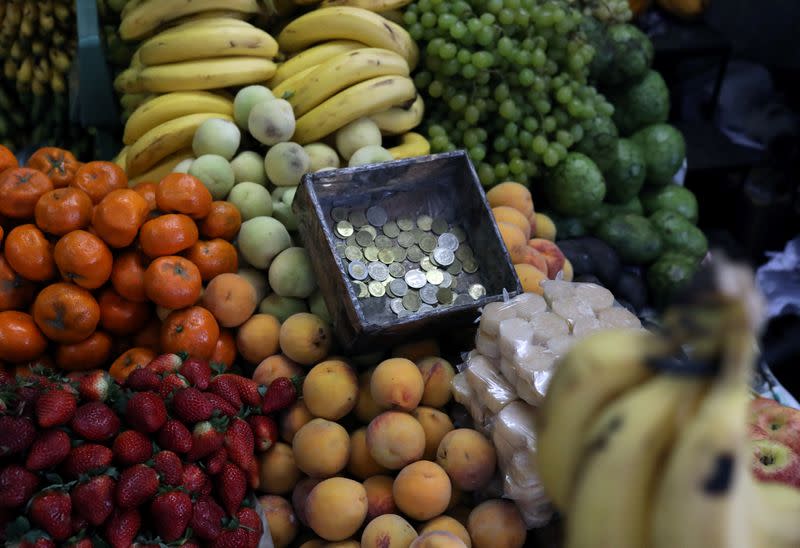 Foto de archivo. Una caja de monedas aparece junto a frutas expuestas para la venta en un puesto del mercado de Surco en Lima