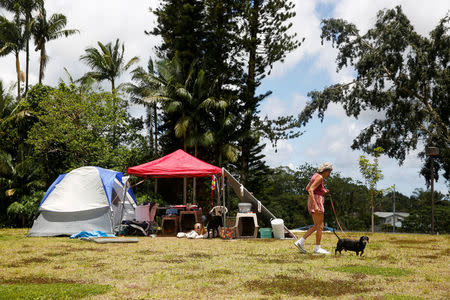 Pauline McLaren, 77, of Kapoho, walks one of her five dogs near her tents at a Red Cross evacuation center in Pahoa during ongoing eruptions of the Kilauea Volcano in Hawaii, U.S., May 15, 2018. REUTERS/Terray Sylvester