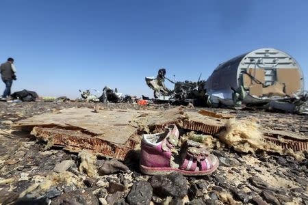 A child's shoe is seen in front of debris from a Russian airliner which crashed at the Hassana area in Arish city, north Egypt, November 1, 2015. REUTERS/Mohamed Abd El Ghany