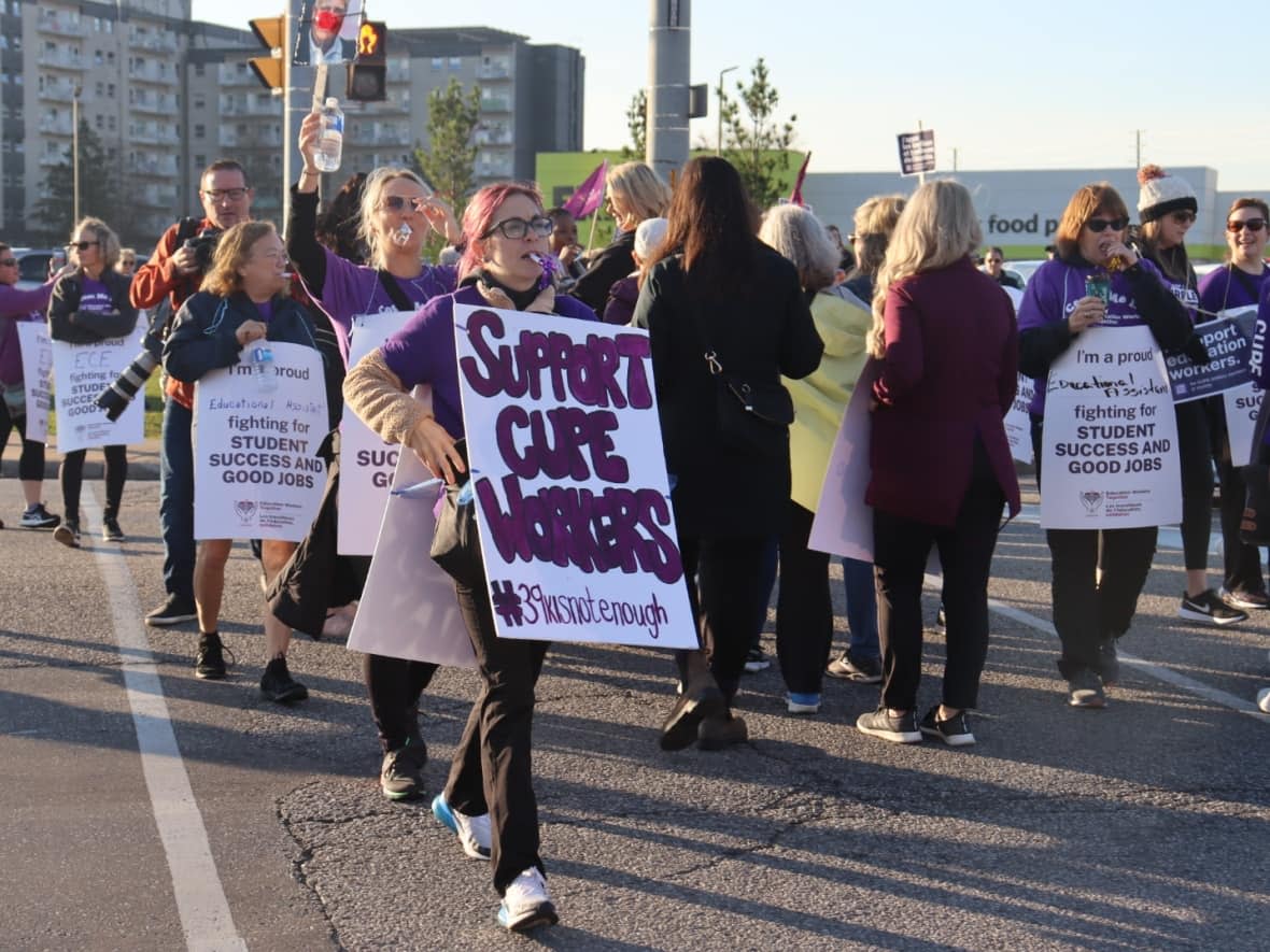 Education workers gather outside Windsor-Tecumseh MPP Andrew Dowie's office on Friday. The English Catholic board closed school buildings amid the strike action. (Jennifer La Grassa/CBC - image credit)