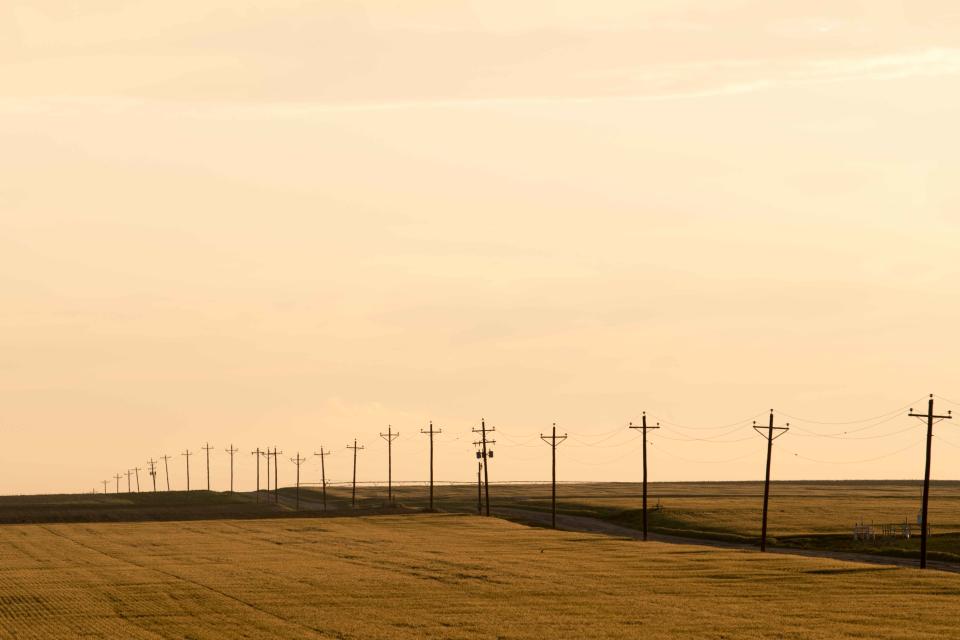 The golden fields in western Kansas are separated by a road and power lines as the sun sets in 2018.