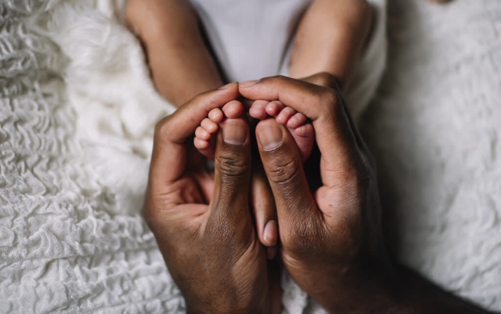 A pair of hands holding a baby's feet.