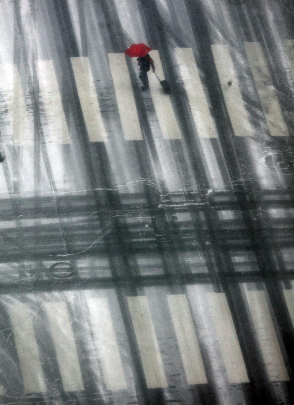 A lone pedestrian pulls a bag while crossing Market Street in downtown Philadelphia as light snow falls Tuesday Jan. 21, 2014. The National Weather Service has issued a winter storm warning for Tuesday's storm with public schools closed in parts of central Pennsylvania and elsewhere while Philadelphia public schools are dismissing classes early. (AP Photo/Jacqueline Larma)