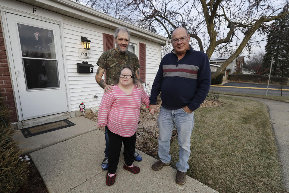 In this Friday, Dec. 20, 2019 photo, Tyrone Cefalu, right, Bobby Goldberg, left, and his sister Debbie Goldberg pose for a photo in front of Bobby Goldberg's home in suburban Chicago. Bobby Goldberg has filed a lawsuit claiming he was abused more than 1,000 times in multiple states and countries by the late Donald McGuire, a prominent American Jesuit priest who had close ties to Mother Teresa. (AP Photo/Nam Y. Huh)