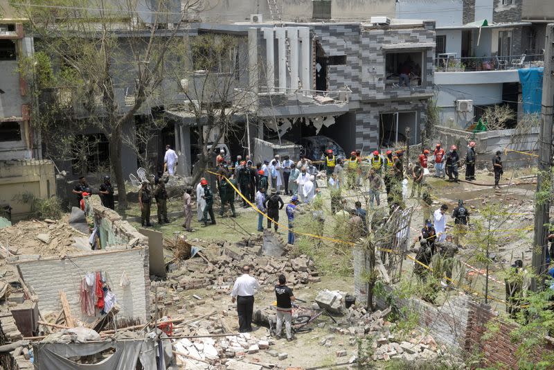 Security officials and rescue workers survey the site after a blast in a residential area in Lahore