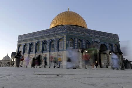 People walk past the Dome of the Rock located on the compound known to Muslims as the Noble Sanctuary and to Jews as Temple Mount, in Jerusalem's Old City May 30, 2015. REUTERS/Ammar Awad