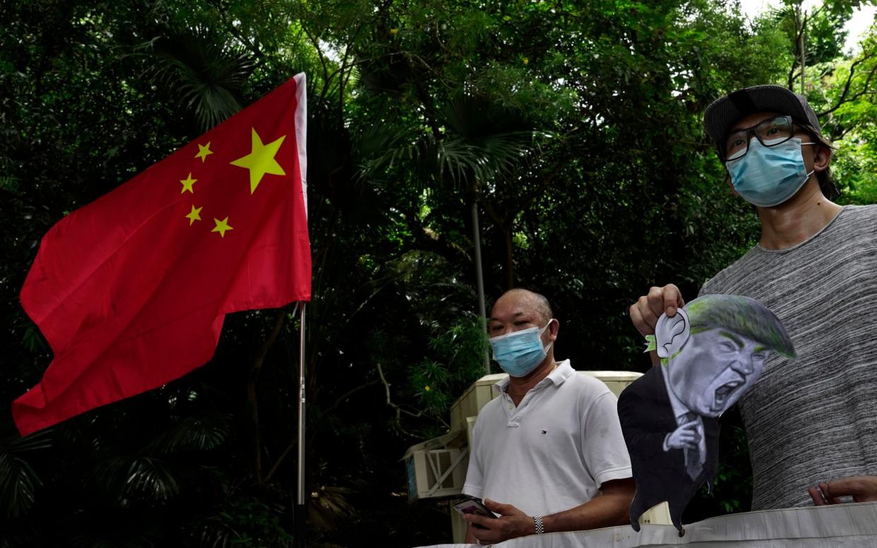 Pro-China supporters displays a picture of Donald Trump during a protest against the sanctions outside the US Consulate in Hong Kong - AP