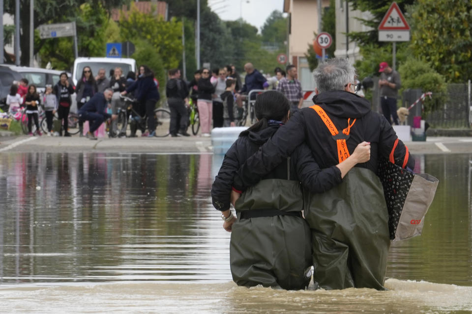 A couple walk in a flooded road of Lugo, Italy, Thursday, May 18, 2023. Exceptional rains Wednesday in a drought-struck region of northern Italy swelled rivers over their banks, killing at least eight people, forcing the evacuation of thousands and prompting officials to warn that Italy needs a national plan to combat climate change-induced flooding. (AP Photo/Luca Bruno)