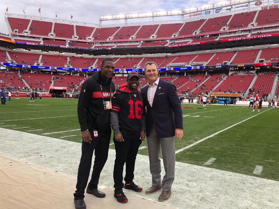 49ers fan Malcolm Scott, center, who spent 22 years in prison for a crime he didn’t commit, was a guest of the team at its game against Seattle on Sunday. Here he poses with former San Francisco linebacker Keena Turner and general manager John Lynch. (49ers/Twitter)