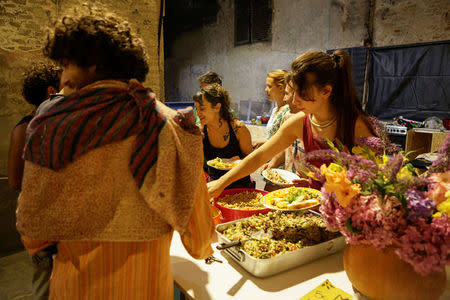 Members of the "Assemblea Cavallerizza 14:45" movement serve dinner to visitors of the Cavallerizza Reale building, which is occupied by the movement in Turin, Italy, July 16, 2016. REUTERS/Marco Bello