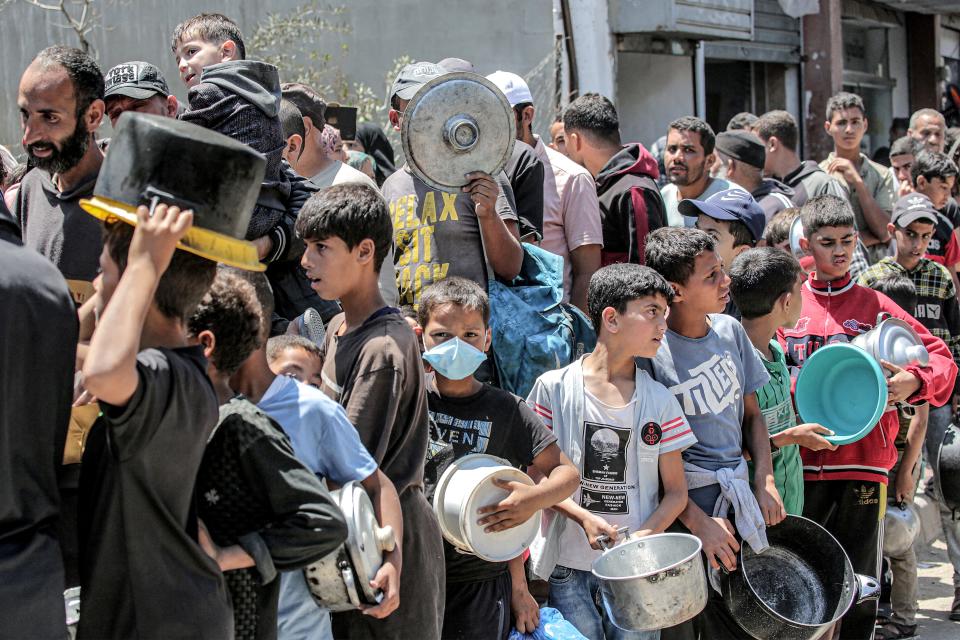 Men and children queue to receive food rations from a public kitchen in Deir el-Balah in the central Gaza Strip on May 13, 2024.