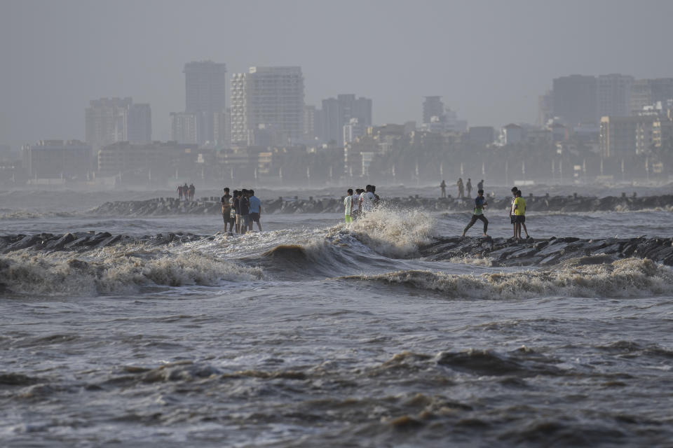 People watch as high tide waves hit the Arabian Sea coast at Juhu Koliwada in Mumbai, India, Monday, June 12, 2023. Cyclone Biparjoy, the first severe cyclone in the Arabian Sea this year is set to hit the coastlines of India and Pakistan Thursday. (AP Photo/Rafiq Maqbool)