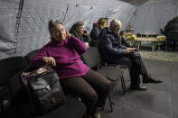 People warm themselves and charge their electronic devices in the heating tent "Point of Invincibly" in Kyiv, Ukraine, Monday, Nov. 28, 2022. (AP Photo/Evgeniy Maloletka)