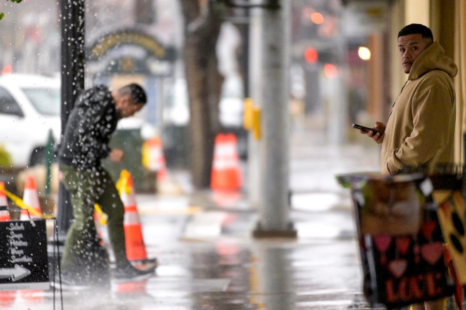Pedestrians walk Downtown during Thursday's downpour in Visalia.