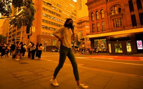 A woman wearing a mask walks in the CBD as smokey haze blankets Sydney, Australia, 06 December 2019 - Credit: REX