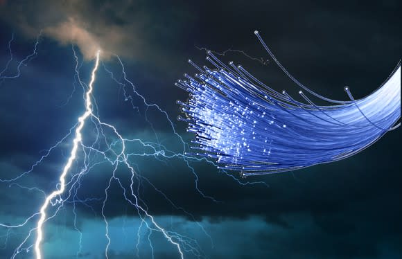 A bundle of fiber-optic cable strands in front of dark clouds and a lightning bolt.