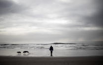 Carmall Casey walks with her dogs on the beach in Hellyer, Tasmania, Australia, Wednesday, July 24, 2019. "It's like freedom when I'm on the beach," said Casey. "I look at the footprints and different shells and it helps to release all my stress and worries." (AP Photo/David Goldman)