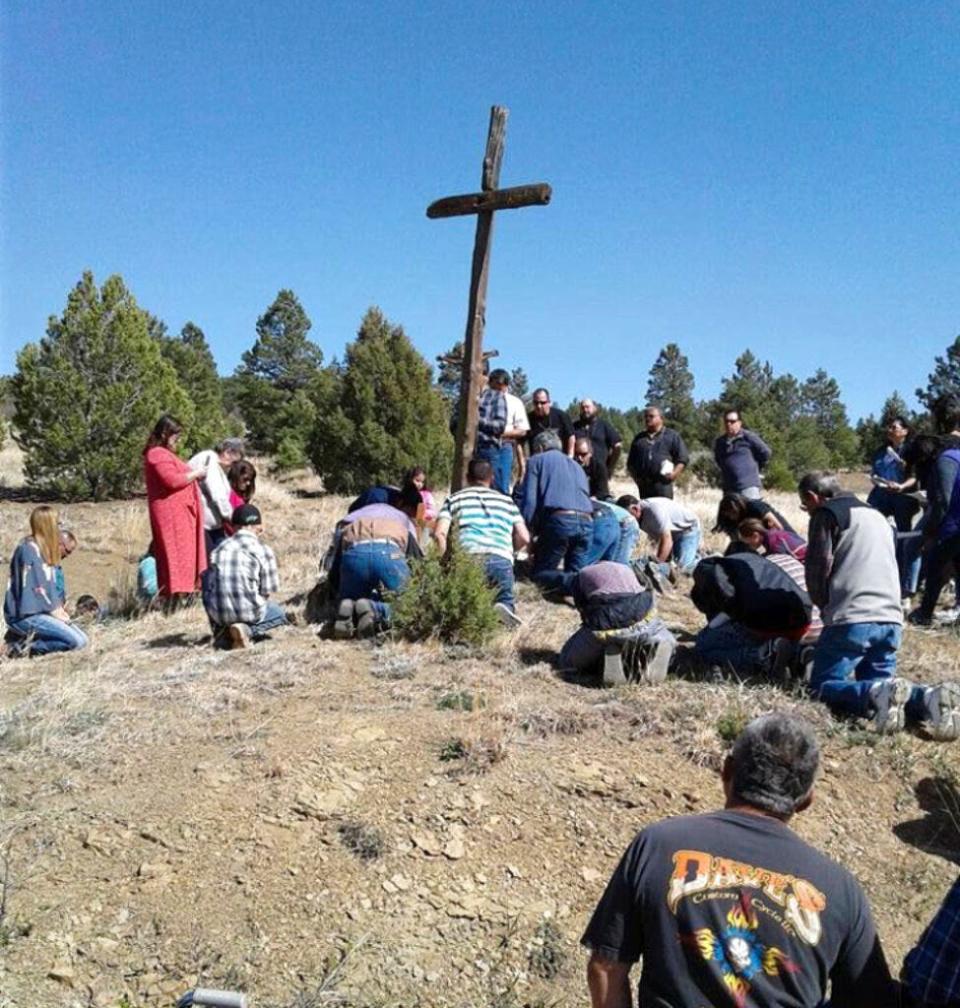 This April 14, 2017, photo provided by Fidel Trujillo shows a group praying at the foot of a cross on Good Friday in Holman, New Mexico. Residents of the community were forced to evacuate because of a wildfire that has marched across 258 square miles of high alpine forest and grasslands at the southern tip of the Rocky Mountains.
