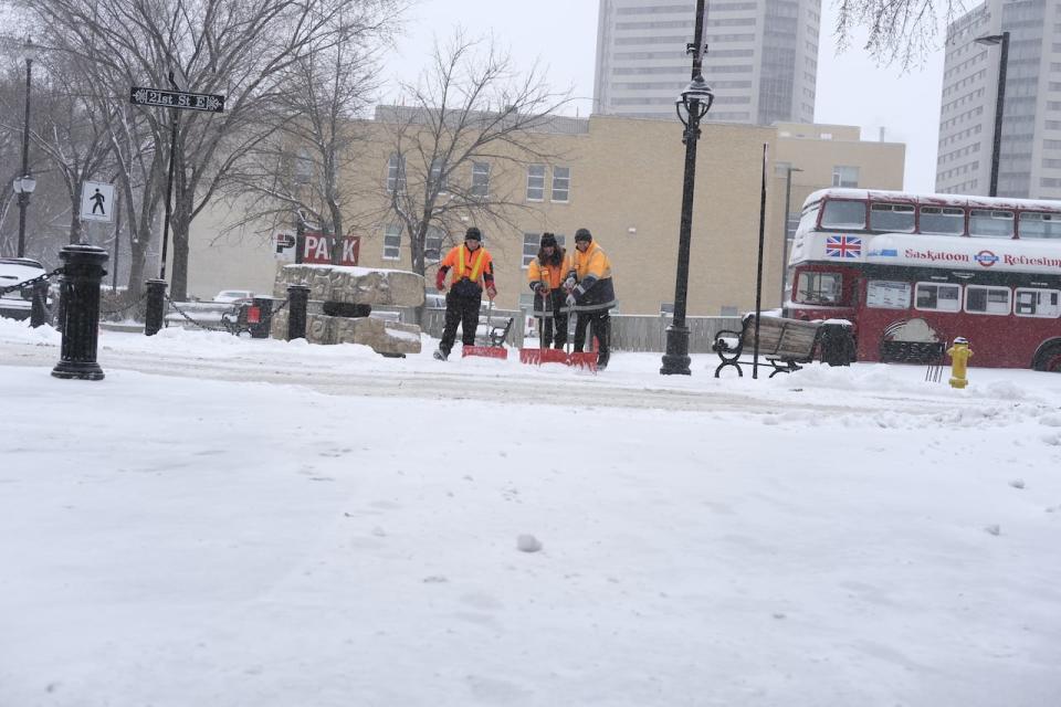 Three city workers are shoveling snow in downtown Saskatoon after the second straight day of snowfall in the city on April 18, 2024. 