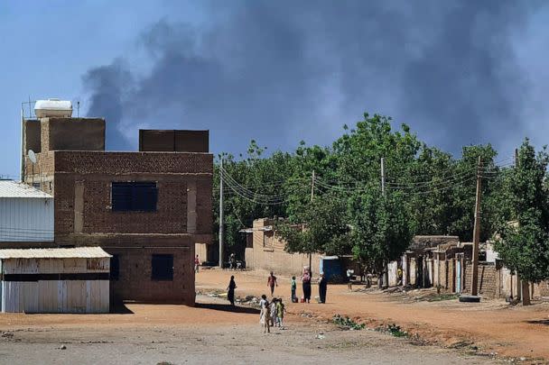 PHOTO: FILE - People walk as smoke billows in the background during fighting in the Sudanese capital Khartoum, May 3, 2023. (-/AFP via Getty Images, FILE)