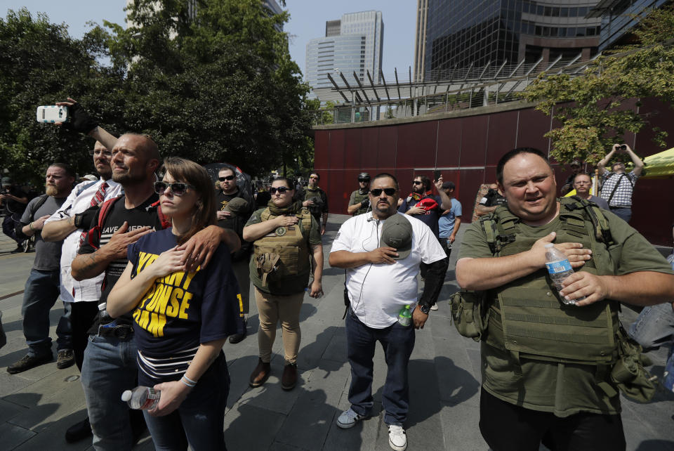 Supporters of a rally held by members of Patriot Prayer and other groups advocating for gun rights stand during a playing of a recording of the national anthem, Saturday, Aug. 18, 2018, at City Hall in Seattle. (AP Photo/Ted S. Warren)