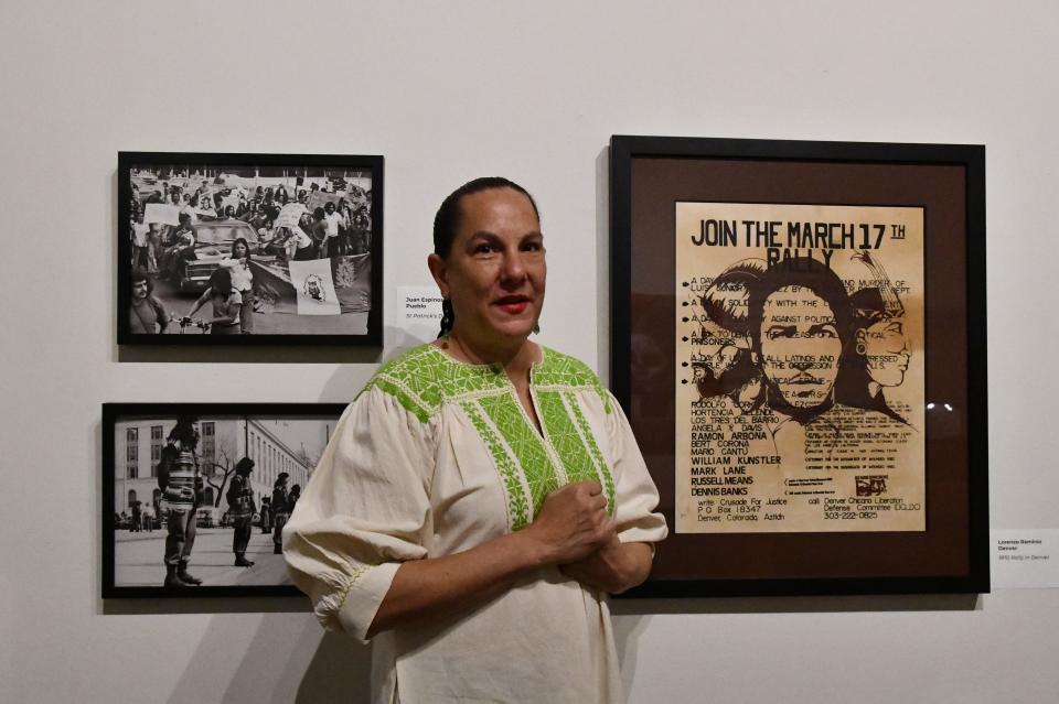Mexican-American art collector Adrianna Abarca stands between a protest poster and photos from the 1970s. The historic works of art are part of an exhibit of Chicano art at El Pueblo History Museum in Pueblo, Colo., until the end of 2022.