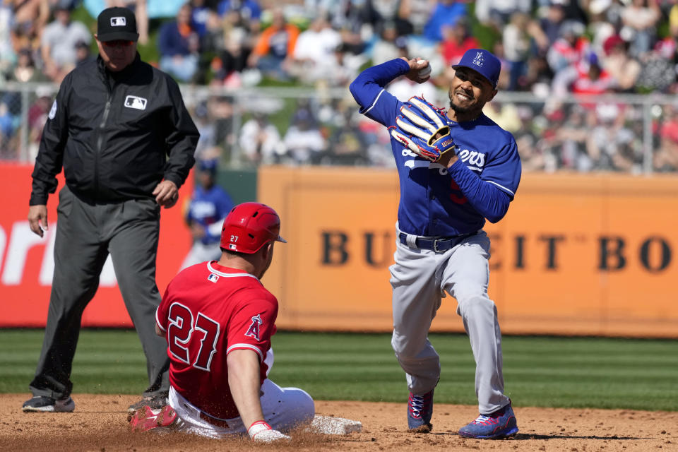 Los Angeles Dodgers second baseman Mookie Betts, right, throws to first base after forcing out Los Angeles Angels' Mike Trout (27) as umpire Doug Eddings, left, looks on during the third inning of a spring training baseball game Friday, March 3, 2023, in Tempe, Ariz. (AP Photo/Ross D. Franklin)