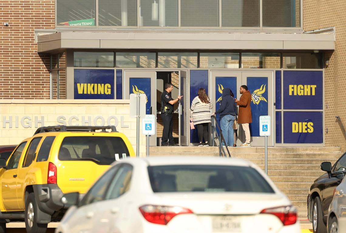 A police officer speaks to people outside of Lamar High School in Arlington during a lockdown on Monday, March 20, 2023. One student was killed and another injured in a shooting Monday morning. Arlington police have arrested a teenage suspect.