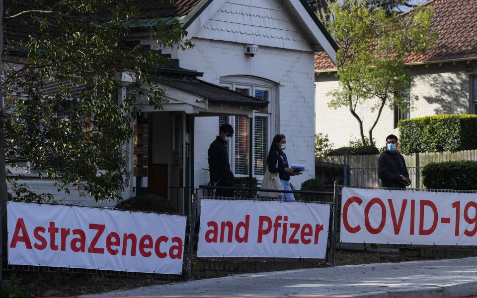People pass a doctor's surgery offering the AstraZeneca and Pfizer vaccines in the suburb of Lane Cove, Sydney - Getty