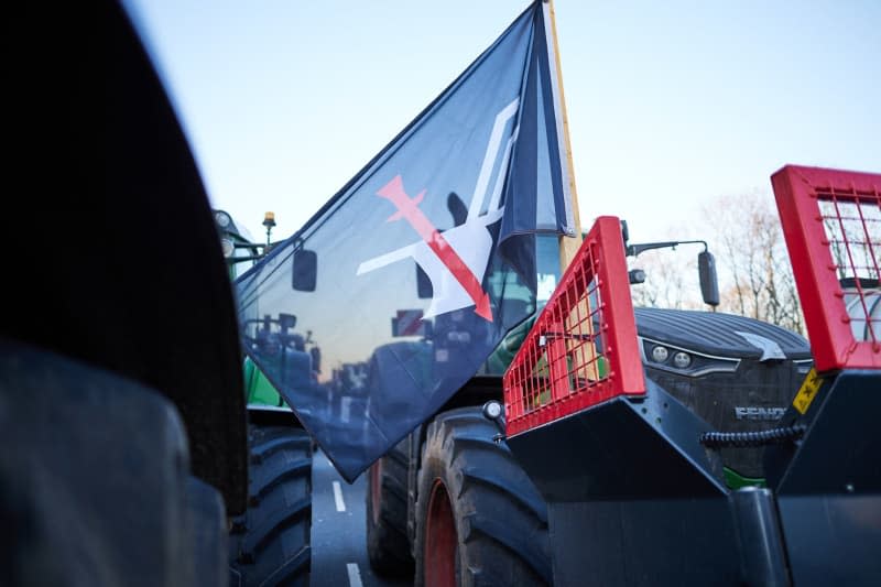 A flag of the Schleswig-Holstein farmers' movement can be seen on a tractor during a farmers' protest in front of the Brandenburg Gate. In response to the federal government's austerity plans, the farmers' association has called for a week of action with rallies and rallies starting on January 8. It is to culminate in a major demonstration in the capital on January 15. Jörg Carstensen/dpa