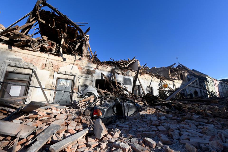 This photograph taken on December 29, 2020, shows the wreckage of a car and damaged buildings in Petrinja, some 50kms from Zagreb, after the town was hit by an earthquake of the magnitude of 6.4. - The tremor, one of the strongest to rock Croatia in recent years, collapsed rooftops in Petrinja, home to some 20,000 people, and left the streets strewn with bricks and other debris. Rescue workers and the army were deployed to search for trapped residents, as a girl was reported dead. (Photo by DENIS LOVROVIC / AFP) (Photo by DENIS LOVROVIC/AFP via Getty Images)