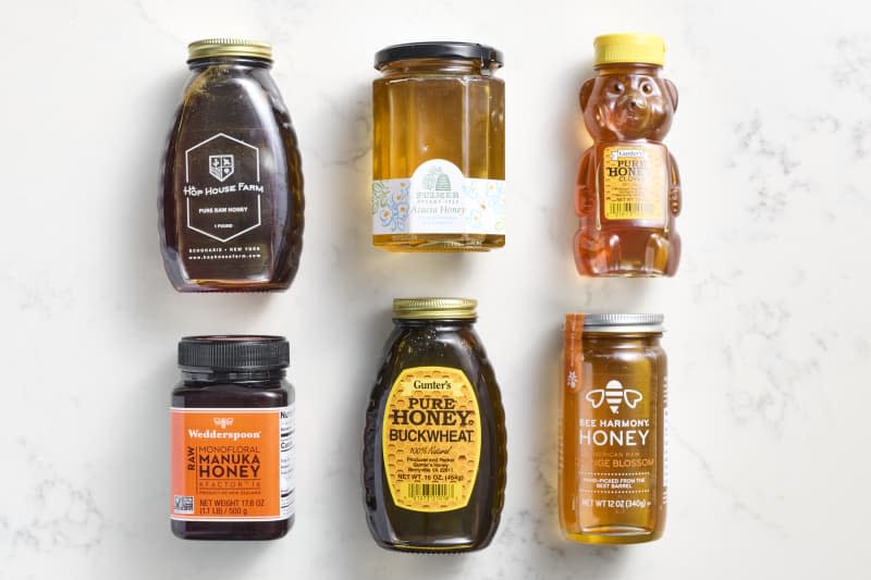 overhead shot of six honeys, from left to right: 
Hop house farm, Fulmer Acacia honey, Gunter's pure clover honey, Wedderspoon Raw Manuka honey, Gunter's pure buckwheat honey and Bee harmony Orange blossom honey