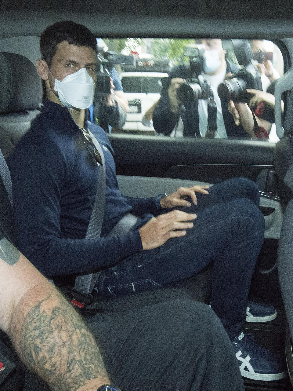 Serbian tennis player Novak Djokovic rides in car as he leaves a government detention facility before attending a court hearing at his lawyers office in Melbourne, Australia, Sunday, Jan. 16, 2022. A federal court hearing has been scheduled for Sunday, a day before the men's No. 1-ranked tennis player and nine-time Australian Open champion was due to begin his title defense at the first Grand Slam tennis tournament of the year. (James Ross/AAP via AP)