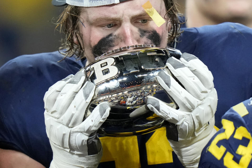 Michigan linebacker Kechaun Bennett kisses the trophy as he celebrates with teammates after defeating Purdue in the Big Ten championship NCAA college football game, early Sunday, Dec. 4, 2022, in Indianapolis. Michigan won, 43-22. (AP Photo/AJ Mast)