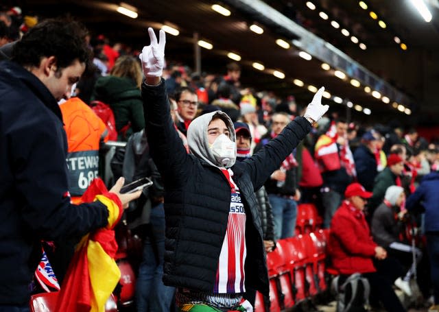 An Atletico Madrid fan wears a mask and gloves in the crowd at Anfield