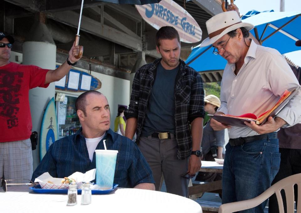 This image released by Universal Pictures shows actors John Travolta, left, and Taylor Kitsch, center, with director Oliver Stone during the filming of "Savages." (AP Photo/Universal Pictures, Francois Duhamel)